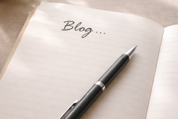 Notebook with the word blog written at the top and a pen placed on the page representing starting a blog with no ideas
