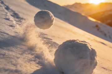 Two snowballs rolling downhill on a snowy mountain slope at sunrise, symbolizing the steady growth and momentum of an email list over time.